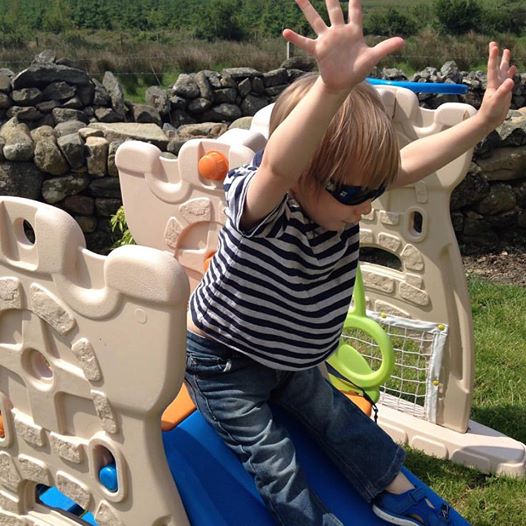 Toddler going down the slide in sunglasses